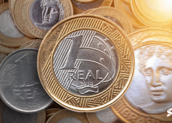 Moeda de 1 real de 2014 em destaque sobre várias outras moedas brasileiras