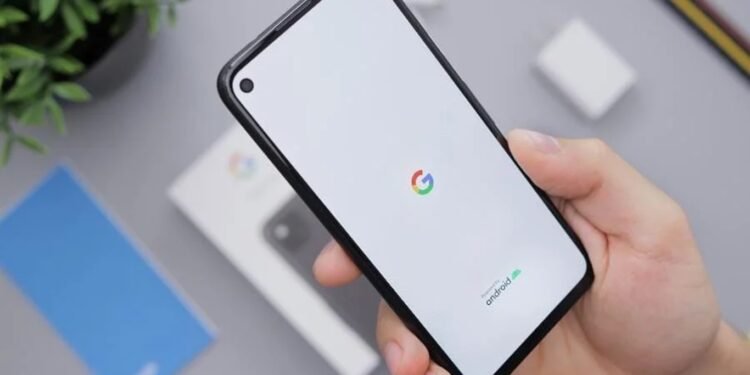Pessoa segurando celular Android novo com logo do Google na tela durante processo de inicialização