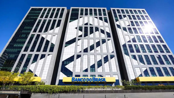 Prédio do Banco do Brasil e Concurso 2025: Edital Próximo. Fachada moderna de um prédio do Banco do Brasil com grandes janelas e a logo visível, em referência ao concurso 2025.