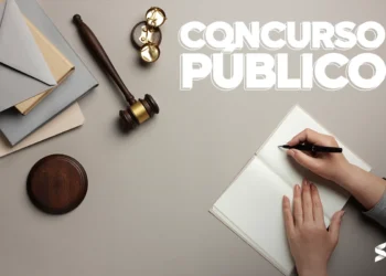 Mão escrevendo em caderno ao lado de martelo judicial, representando preparação para concurso público