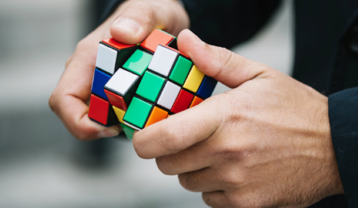 Os 6 elementos que conectam as pessoas inteligentes – A resolução de problemas como habilidade chave. Pessoa resolvendo um cubo mágico, simbolizando as habilidades e a inteligência necessárias para resolver desafios complexos.