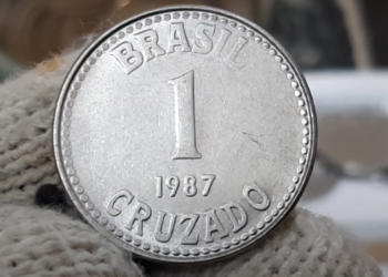 Moeda de 1 cruzado de 1987, com o valor e inscrição 'Brasil' e 'Cruzado', podendo ser uma peça valiosa para colecionadores.