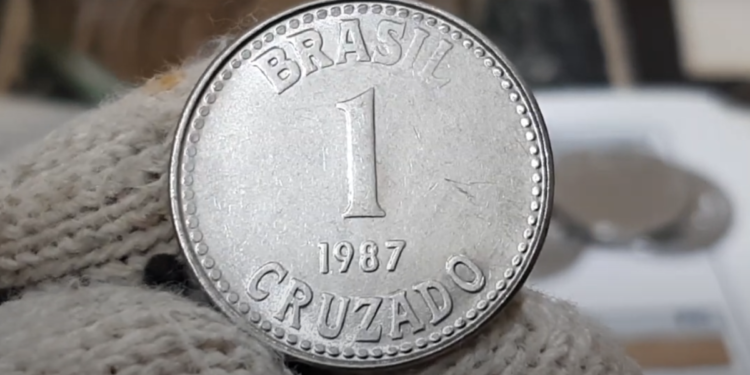 Moeda de 1 cruzado de 1987, com o valor e inscrição 'Brasil' e 'Cruzado', podendo ser uma peça valiosa para colecionadores.