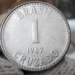 Moeda de 1 cruzado de 1987, com o valor e inscrição 'Brasil' e 'Cruzado', podendo ser uma peça valiosa para colecionadores.