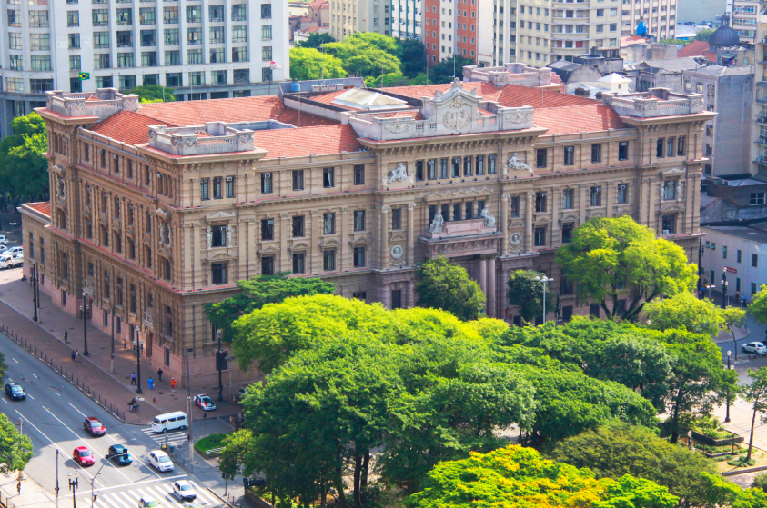 Vista aérea do prédio do Tribunal de Justiça de São Paulo cercado por árvores e prédios no centro da cidade.
