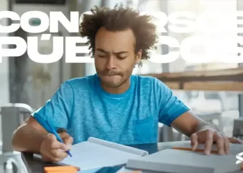 Homem de camiseta azul escrevendo em um caderno, com uma expressão concentrada, indicando a preparação para o concurso