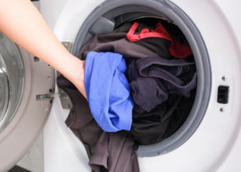 Pessoa colocando roupas coloridas na máquina de lavar, simbolizando economia de energia ao escolher horários mais baratos.