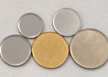 Discos metálicos lisos de diferentes tamanhos, com um destaque em cor dourada.