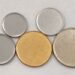 Discos metálicos lisos de diferentes tamanhos, com um destaque em cor dourada.