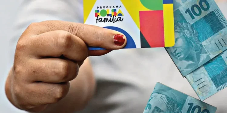 "Imagem do cartão Bolsa Família sendo segurado por uma mão, com cédulas de 100 Reais ao fundo, simbolizando o apoio financeiro."