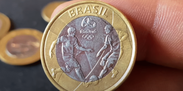Moeda de 1 real das Olimpíadas com erro de cunhagem, mostrando jogadores de futebol.