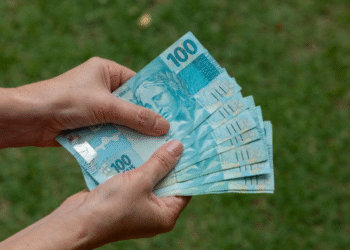 pessoa segurando várias cédulas de 100 reais da segunda família do real