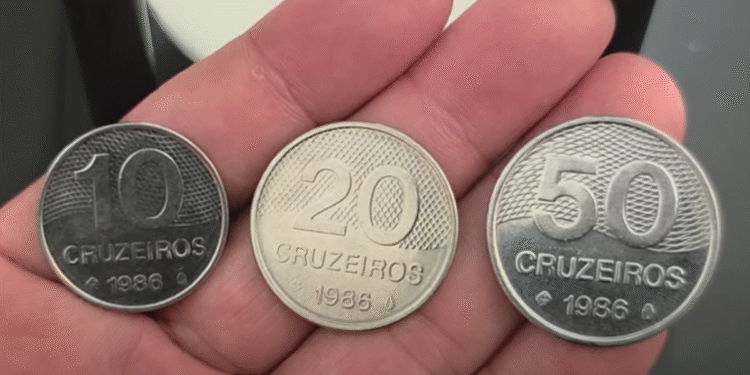 Moedas antigas de cruzeiros brasileiras de 1986, valores 10, 20 e 50 cruzeiros em mão humana Título: Moedas de Cruzeiros de 1986 com Valores 10, 20 e 50