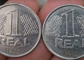 Duas moedas brasileiras de 1 real, datadas de 1994, exibidas sobre os dedos de uma mão.