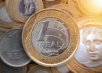 Moeda de 1 real destacada em meio a outras moedas, potencialmente rara por erro de cunhagem.