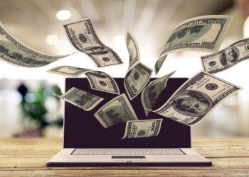 Notas de dólar saindo da tela de um notebook após dicas financeiras do ChatGPT