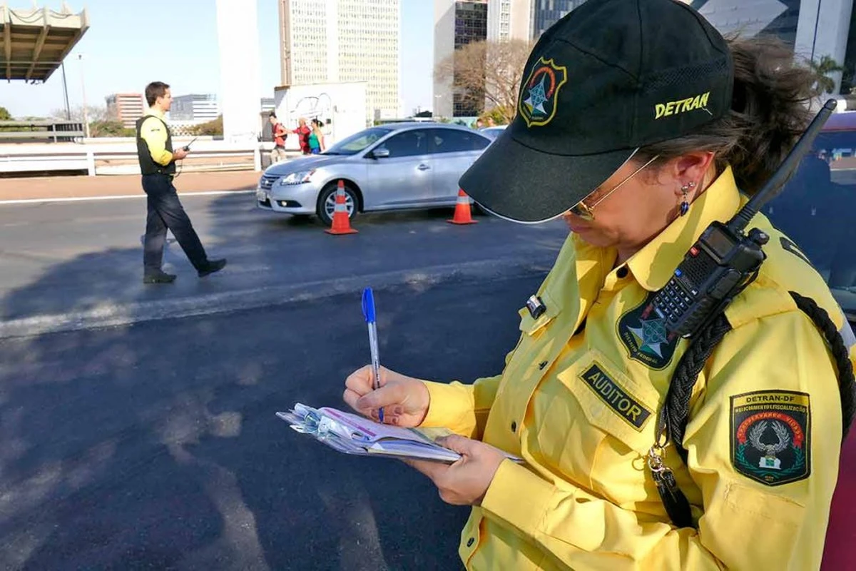Agente de trânsito Agente do Detran do Distrito Federal escrevendo em bloco de notas durante fiscalização de trânsito.