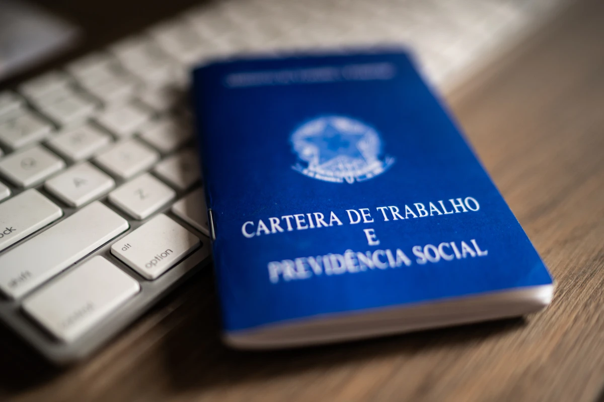 Carteira de Trabalho e Previdência Social sobre teclado de computador, simbolizando trabalho formal.