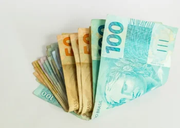 Cédulas de real empilhadas em sequência, destacando as notas de 50 e 100 reais.