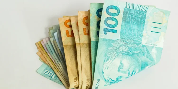 Cédulas de real empilhadas em sequência, destacando as notas de 50 e 100 reais.