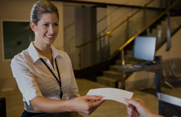 "Funcionária de banco atendendo cliente e realizando tarefas administrativas, representando as funções de um escriturário do Banco do Brasil."