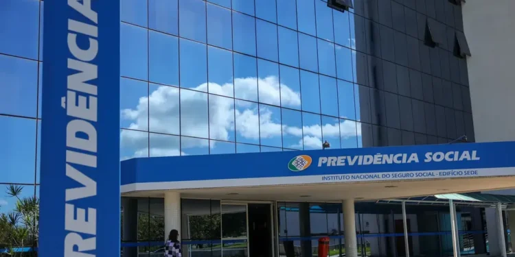 Fachada da sede do INSS com reflexo do céu azul nas janelas espelhadas.