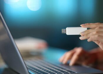 Pessoa inserindo um pendrive em um laptop, mostrando o uso de um dispositivo USB