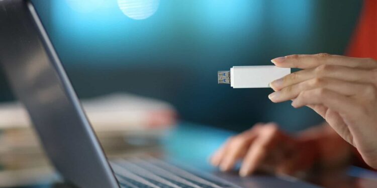 Pessoa inserindo um pendrive em um laptop, mostrando o uso de um dispositivo USB