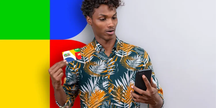 Jovem olhando para celular enquanto segura cartão do programa Bolsa Família com fundo colorido.