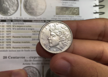 Moeda antiga de 50 centavos do Brasil sendo segurada entre os dedos, mostrando o lado com a efígie da República.