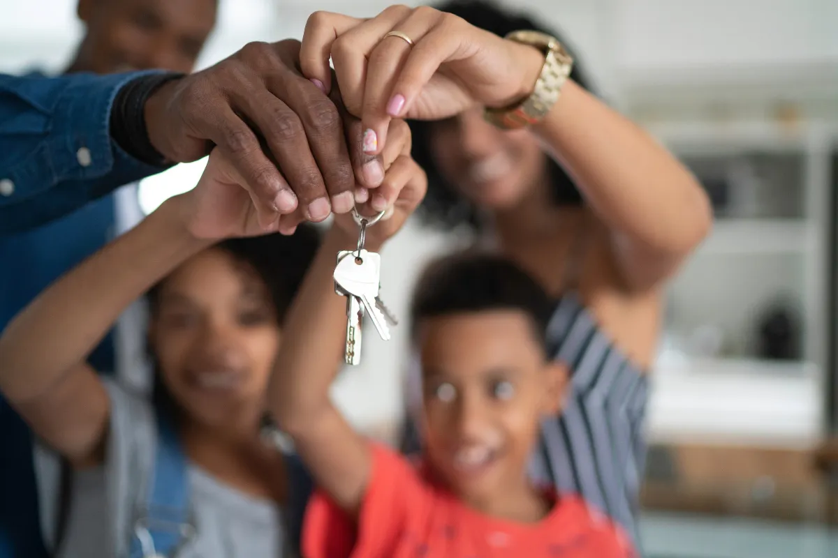 Família feliz segurando as chaves da casa nova simbolizando a conquista da casa própria.