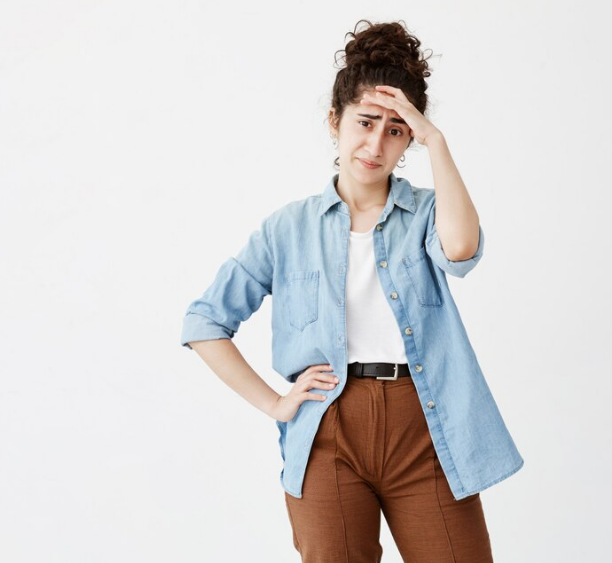 Evite erros que causam insatisfação futura Mulher demonstrando frustração e insatisfação, com a mão na testa e expressão preocupada.