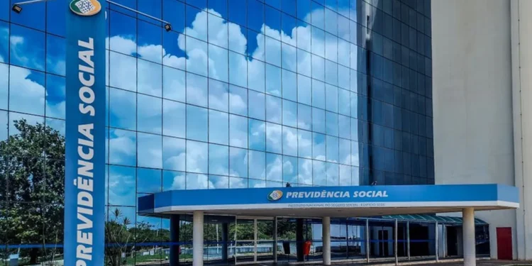 Fachada moderna do edifício da Previdência Social refletindo o céu azul com nuvens.