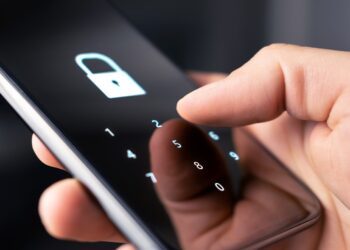 Segurança Digital: Pessoa segurando celular com tela bloqueada mostrando ícone de cadeado e teclado numérico para senha