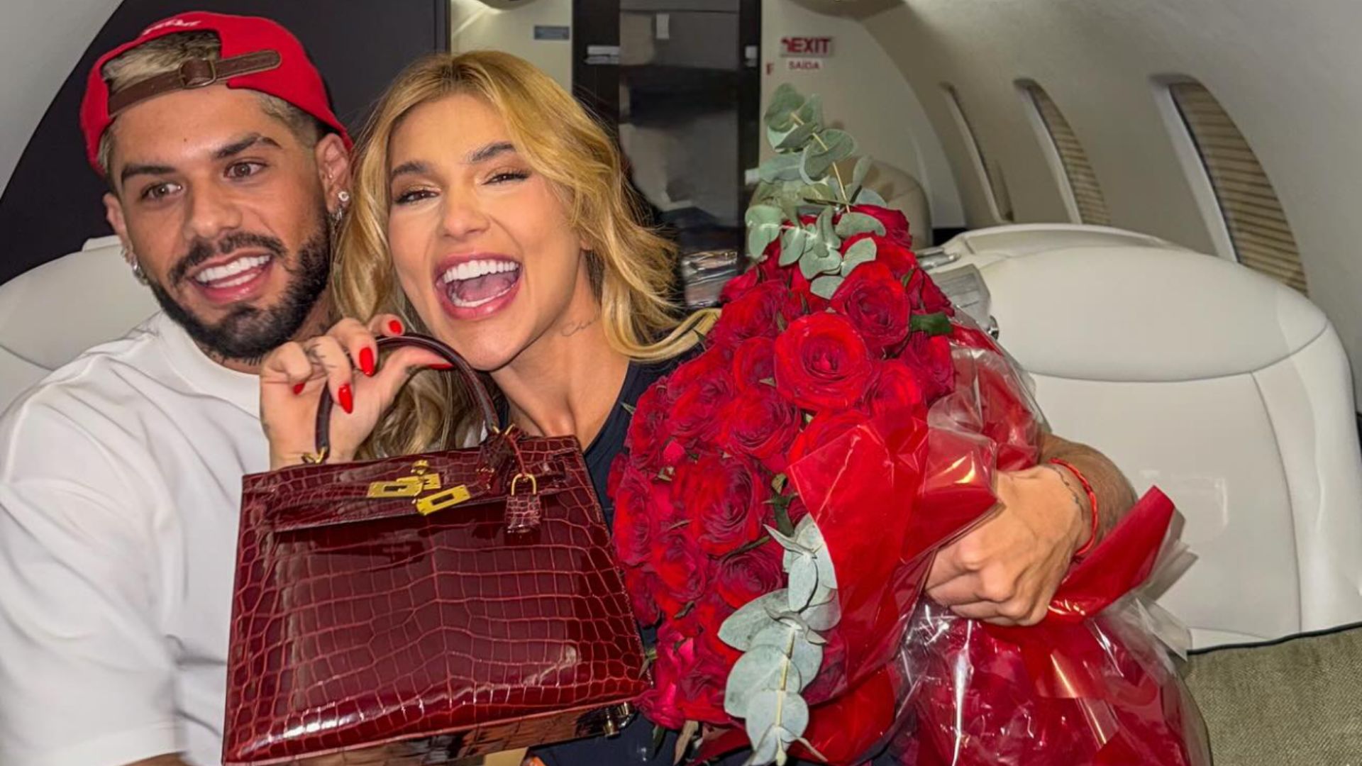 Separação de Virgínia e Zé Felipe Virgínia sorrindo segurando um buquê de rosas e uma bolsa vermelha ao lado de Zé Felipe em um avião particular.