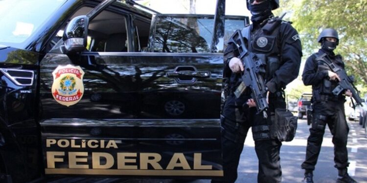 Dois policiais federais armados ao lado de um veículo da Polícia Federal, representando a força e segurança do concurso da PF.