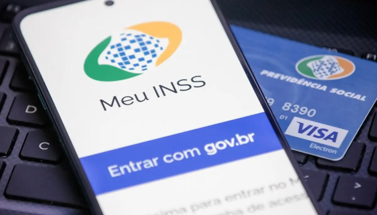 Aplicativo Meu INSS e Cartão de Previdência Social Tela do aplicativo Meu INSS com cartão de Previdência Social ao lado.