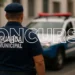 Agente da Guarda Municipal de costas com viatura ao fundo durante concurso público