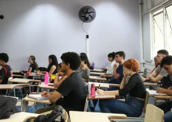 Estudantes concentrados em sala de aula durante aula presencial.
