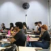 Estudantes concentrados em sala de aula durante aula presencial.