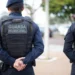 Dois guardas municipais, de costas, usando uniformes azuis e coletes táticos com a inscrição "GUARDA MUNICIPAL".