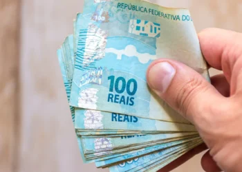 Notas de 100 reais empilhadas na mão.