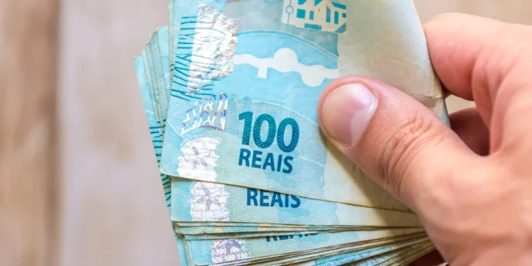 Notas de 100 reais empilhadas na mão.