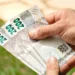 Mãos segurando cédulas de 200 reais representando pagamento de benefícios sociais