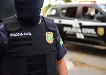 Agente da Polícia Civil com farda e colete, durante operação policial.