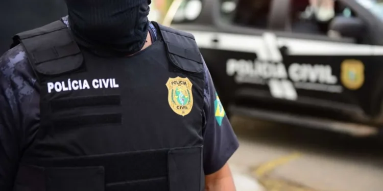 Agente da Polícia Civil com farda e colete, durante operação policial.