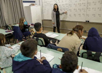 Professora ensinando crianças em sala de aula, representando o ambiente do CNU dos Professores.