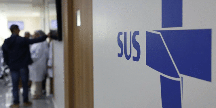 Logo do SUS em hospital, com profissionais e pacientes ao fundo, simbolizando nova parceria com a rede privada.