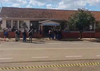Imagem da escola Maria Nascimento Giacomazzi com a presença de policiais em frente, com cordão de isolamento e investigação em andamento.