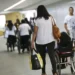 Mulher com bolsa e uma cadeira de rodas em um corredor acessível de uma universidade, representando a inclusão de pessoas com deficiência.